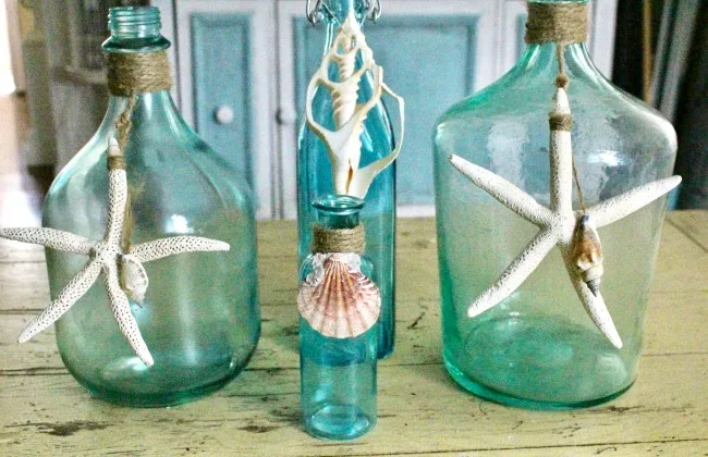 set of four bottles with star fish and sea shells painted blue on coffee table