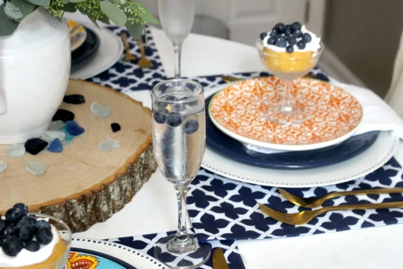 summer tablescape with orange dishes and blueberries in champagne