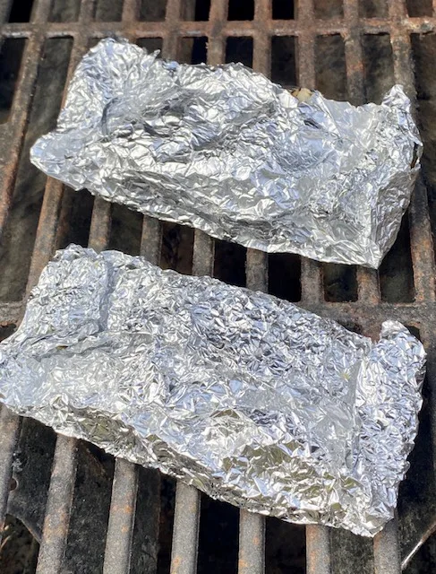 Foil wrapped chicken on grill
