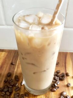 Hazelnut Iced Coffee on counter with coffee beans and straw