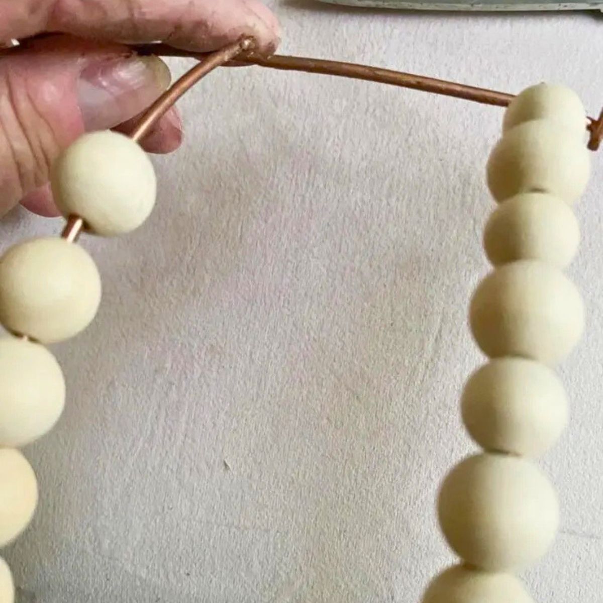 adding wood beads to pumpkin wire wreath form from dollar tree