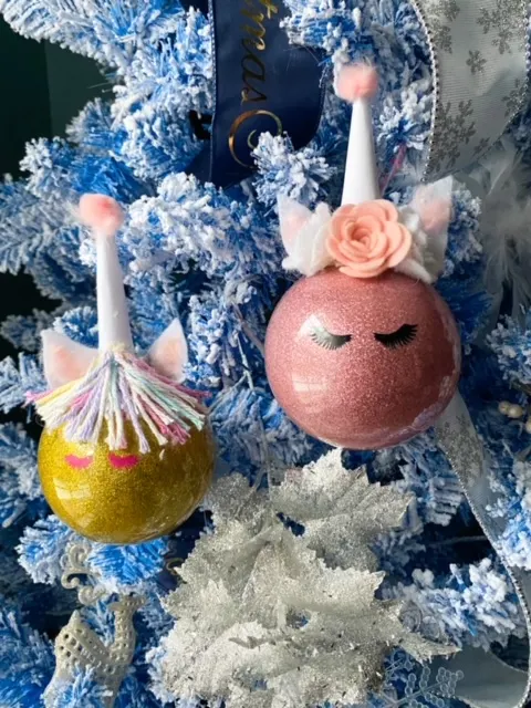 two unicorn ornaments hanging on tree