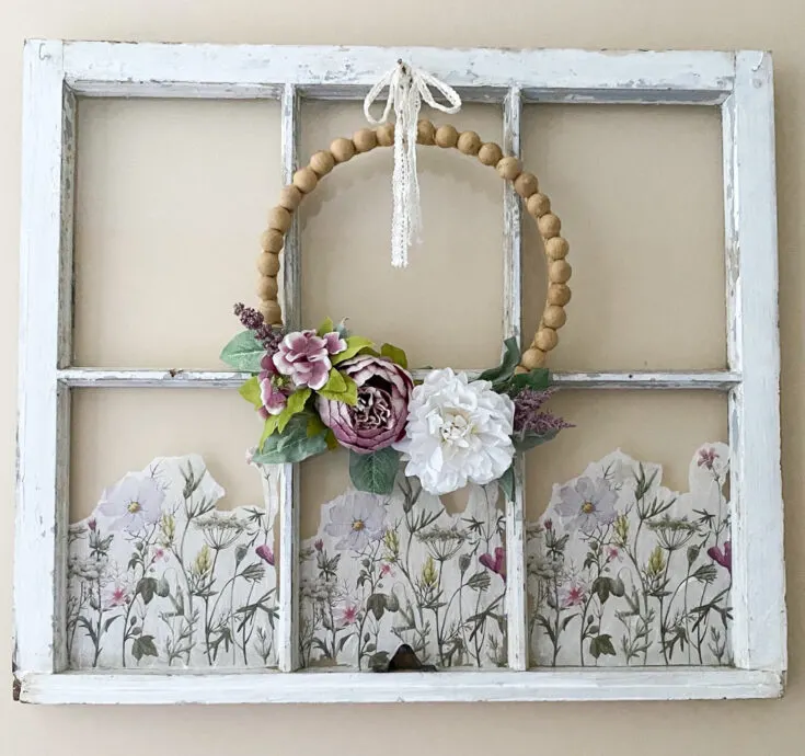 old window hanging on wall with wood bead wreath