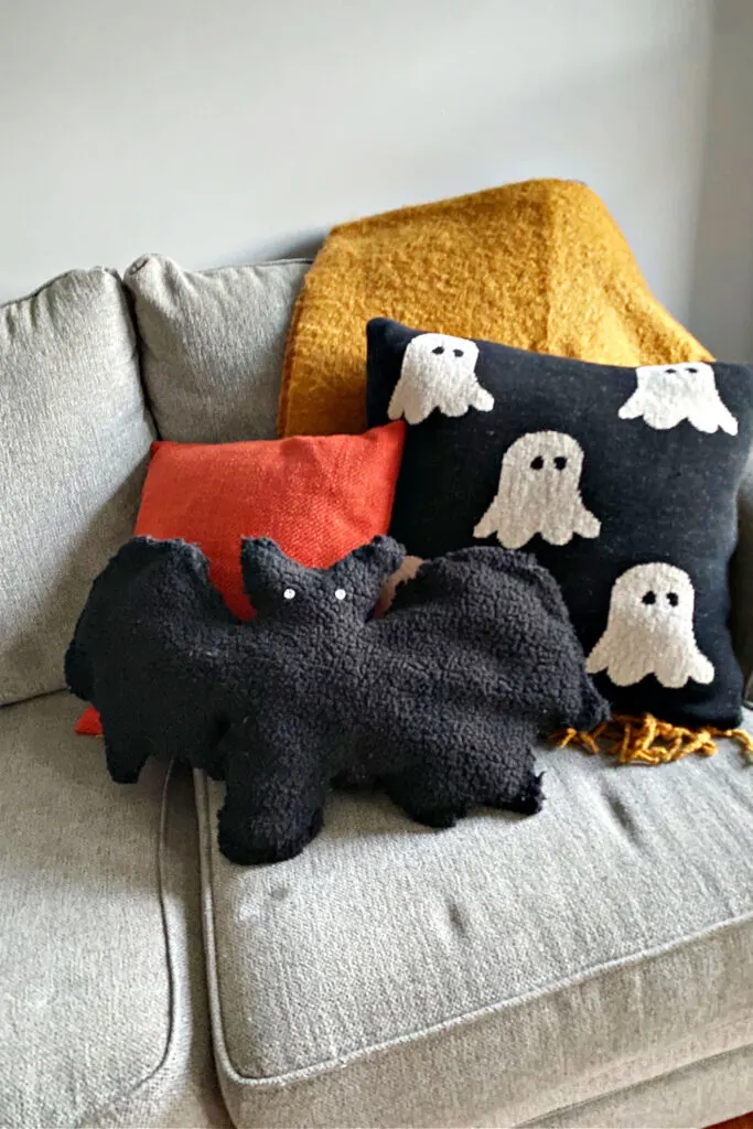 pottery barn dupe bat pillow shown on living room sofa with ghost pillow