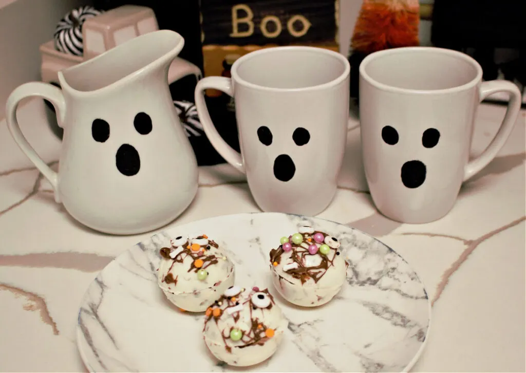 hot chocolate bombs on plate with ghost mugs