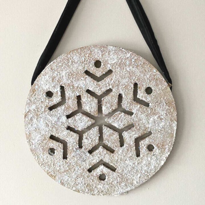 wooden snowflake with glitter hanging on wall