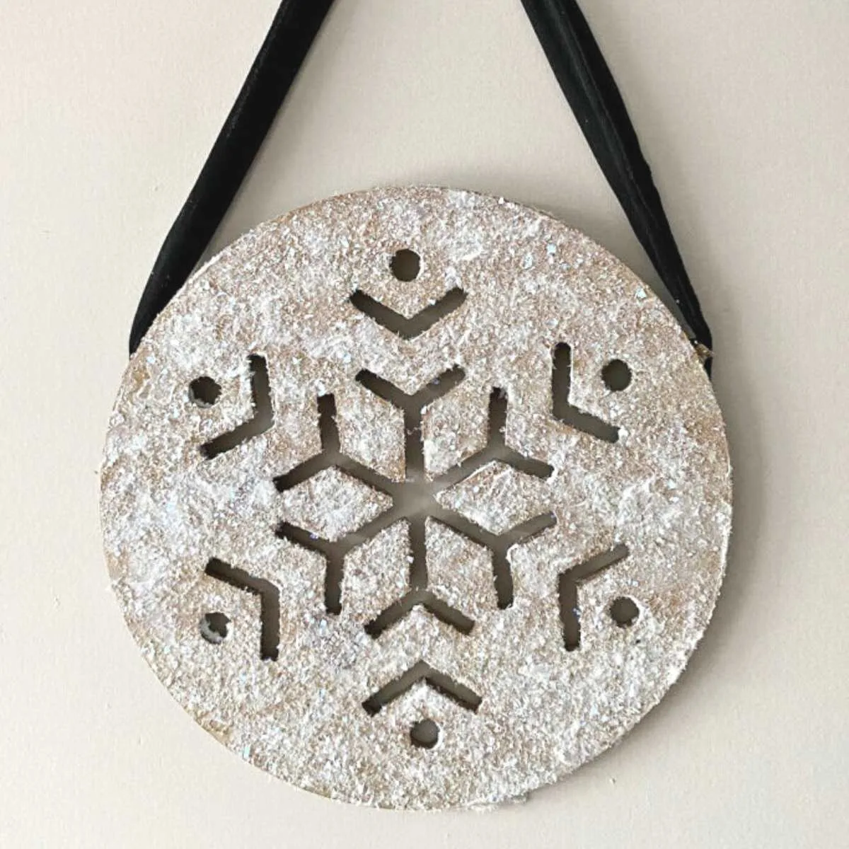 wooden snowflake with glitter hanging on wall