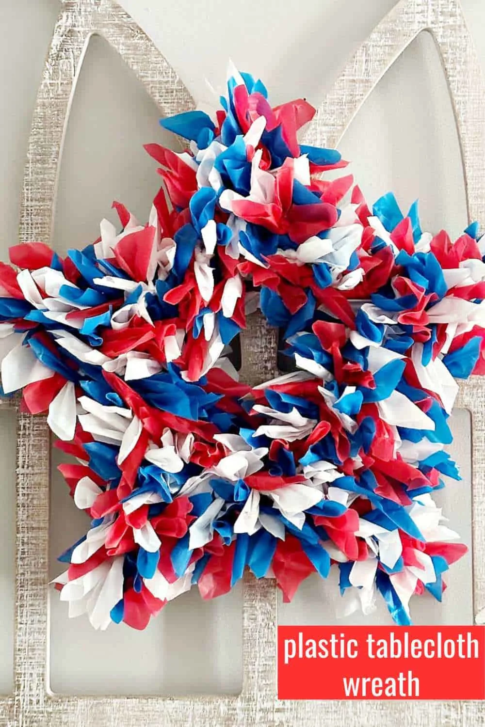 close up of red white and blue plastic tablecloth wreath on frame