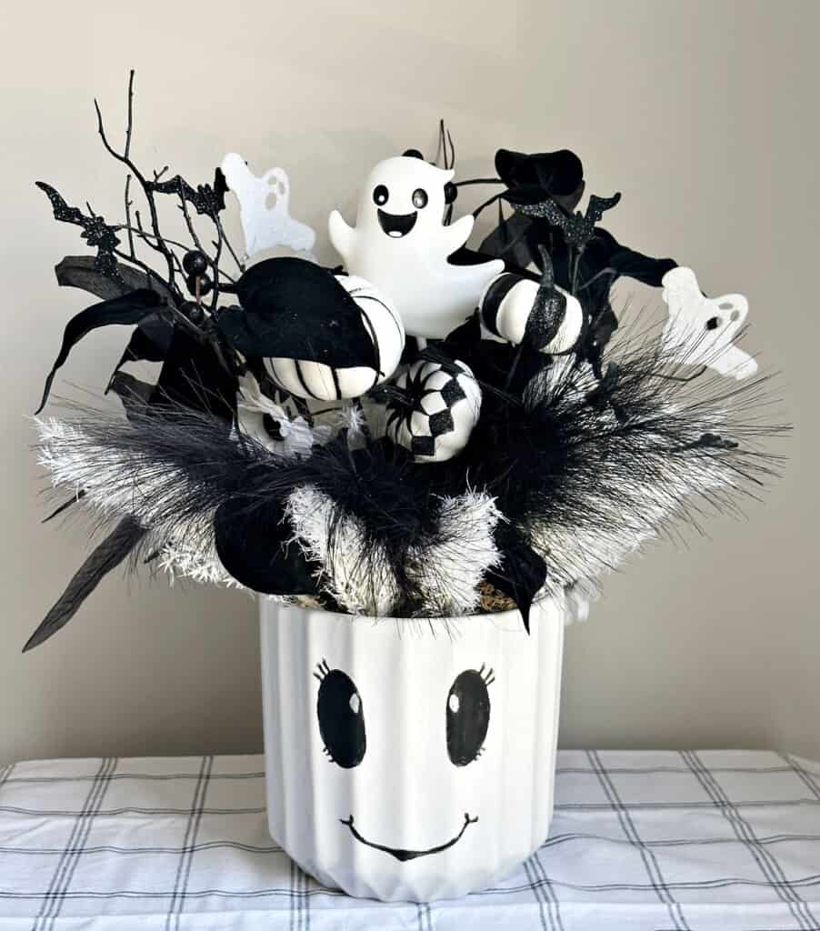 halloween centerpiece with painted ghost face and black and white florals