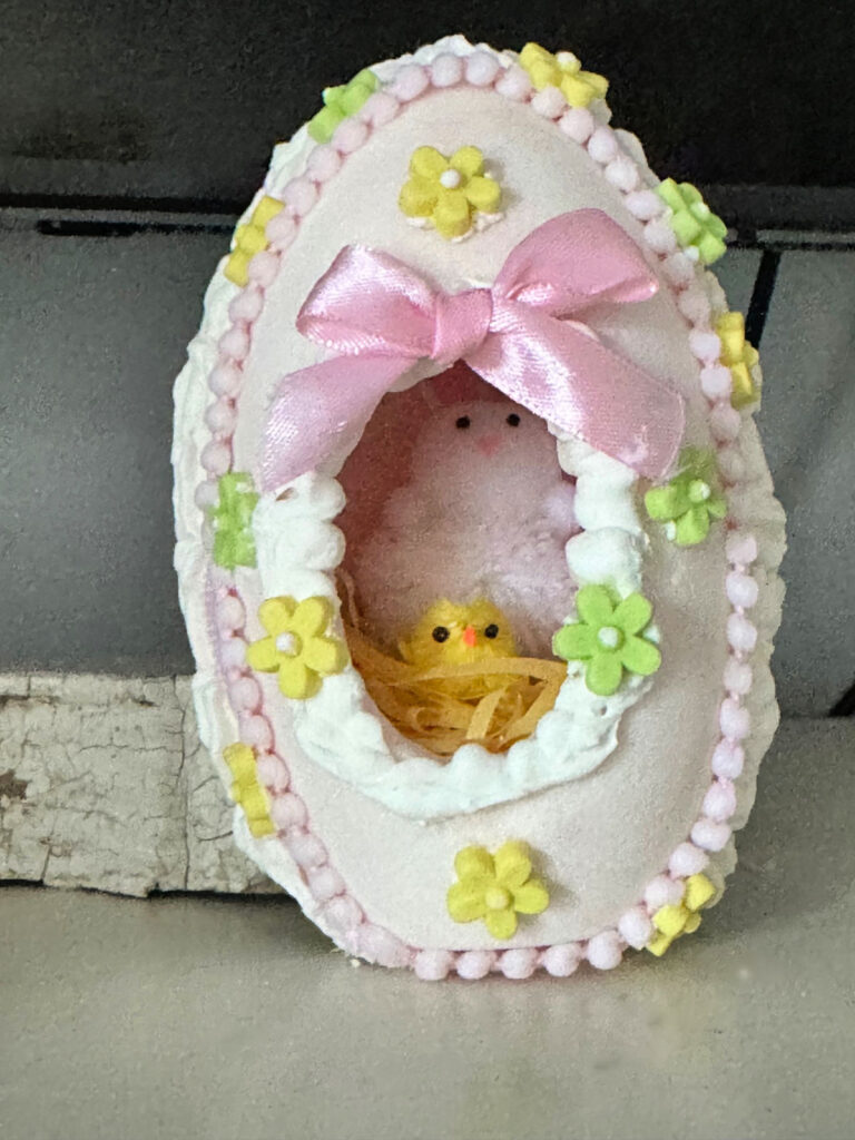 center view of a sugar egg shown on mantel with pom pom bunny