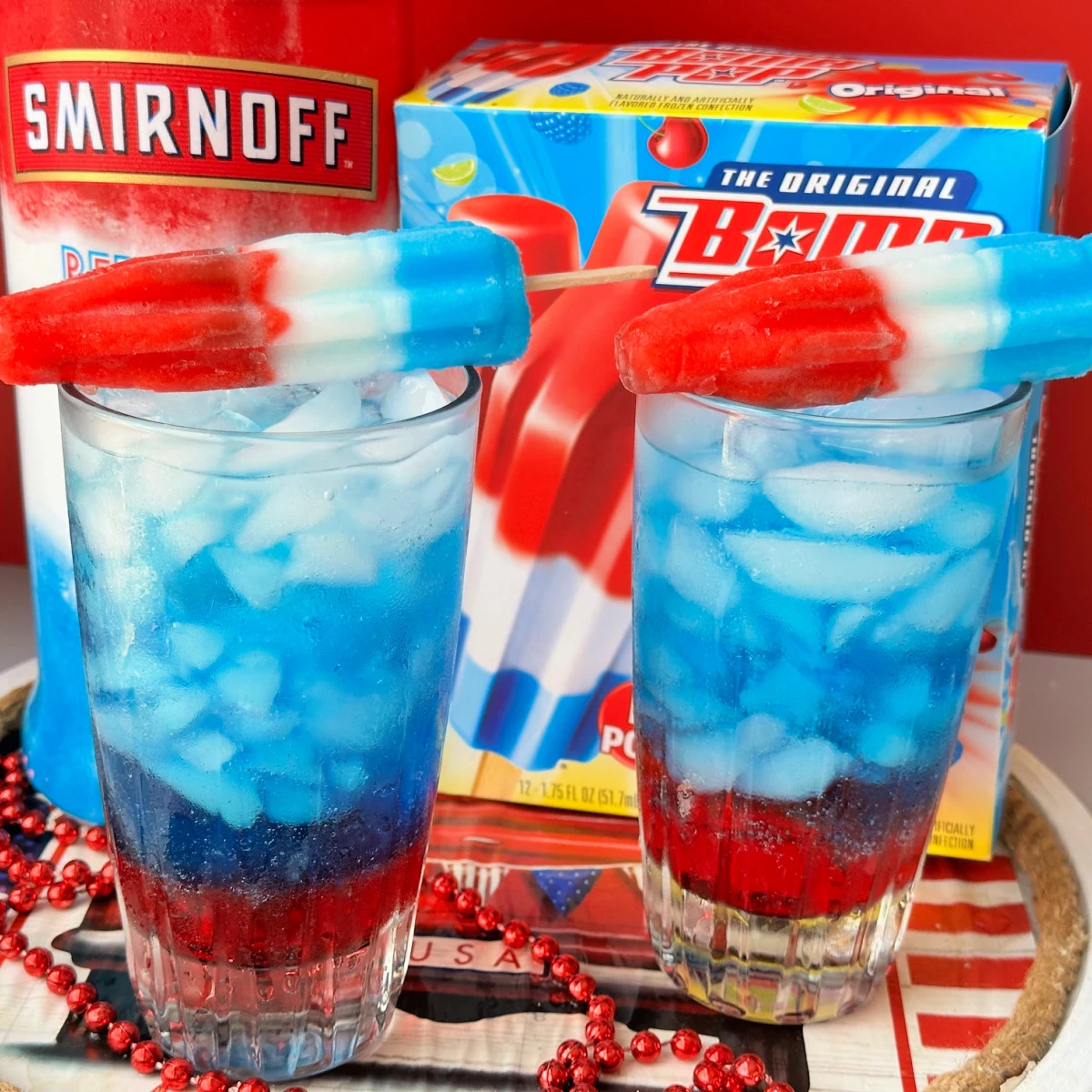 bomb pop cocktail with popsicles on top of glass