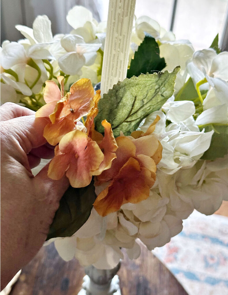 adding fall flowers to candle holder centerpiece