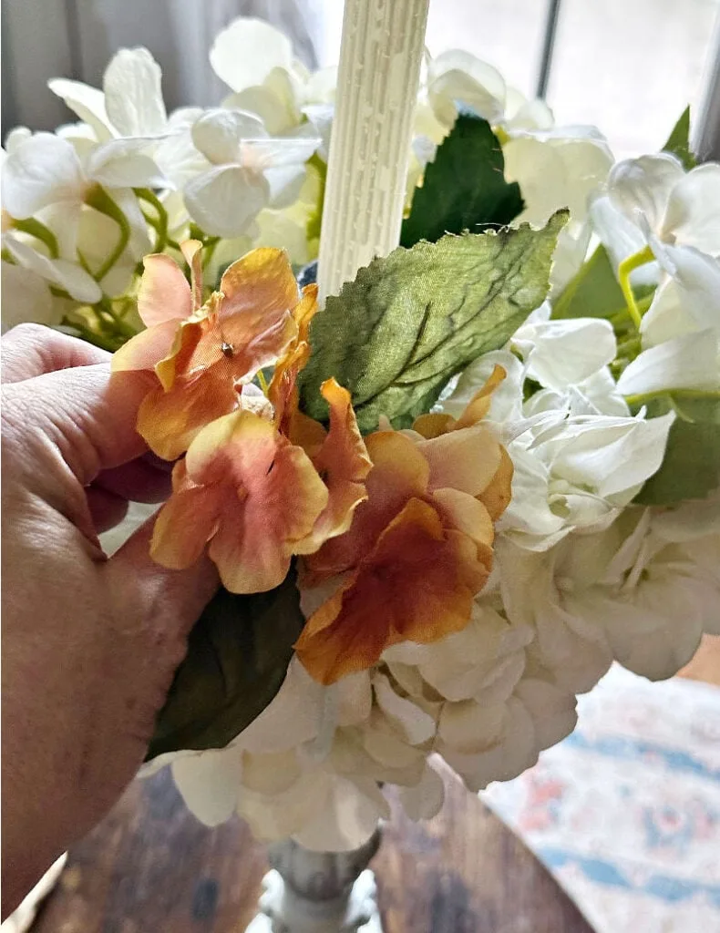 adding fall flowers to candle holder centerpiece