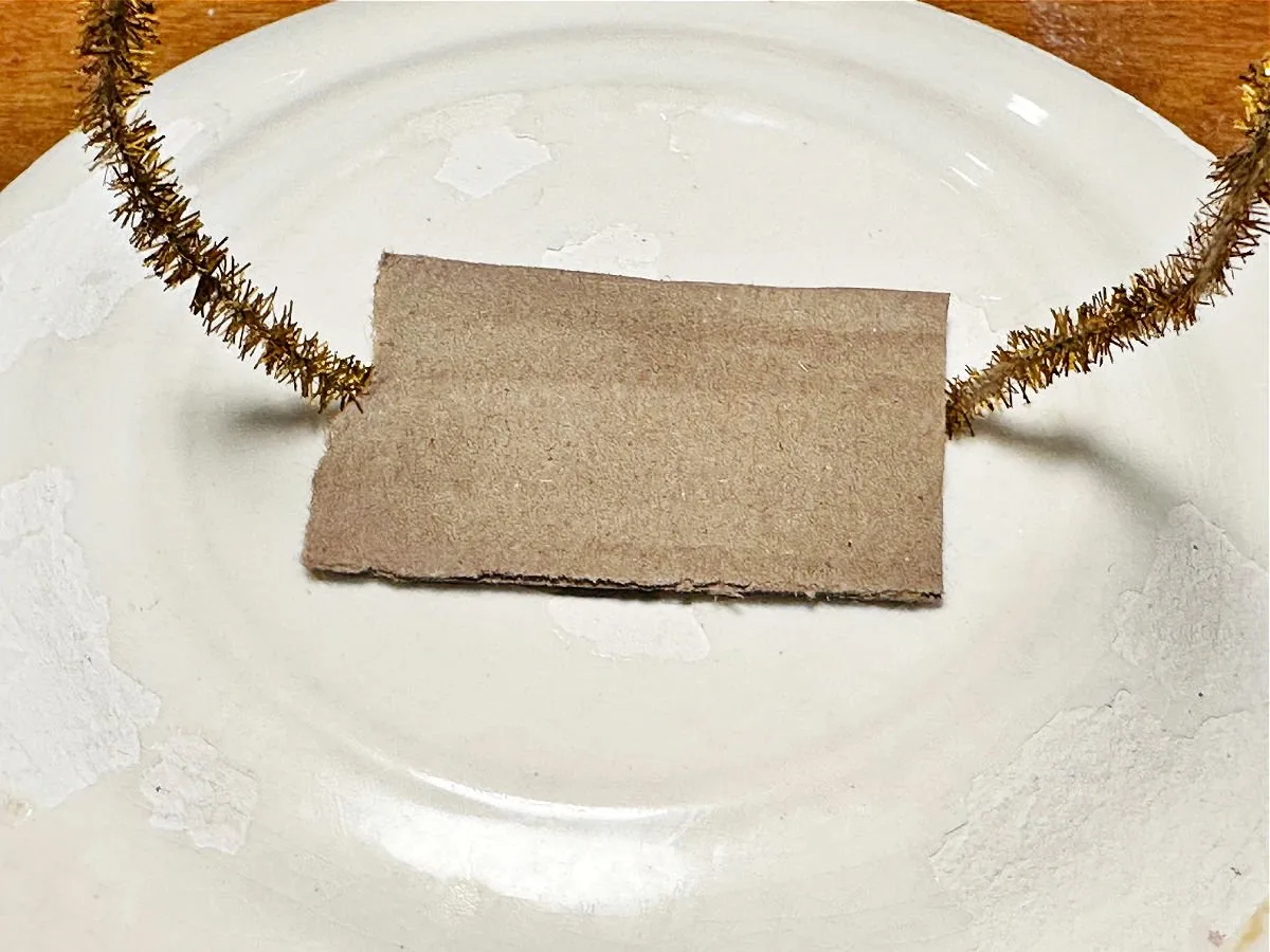 securing pipe cleaner and cardboard to plate