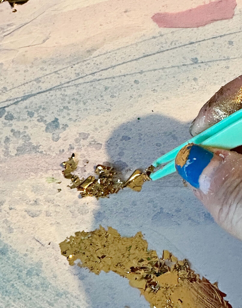 using tweezers to add gold foil to wall art