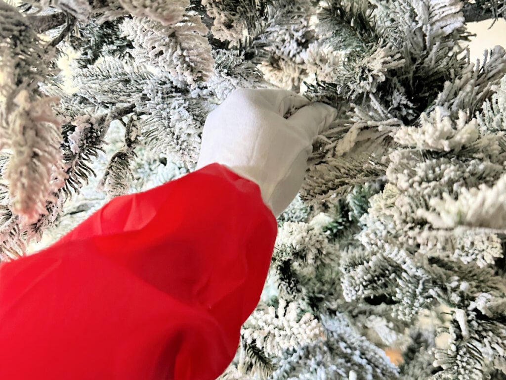 king of christmas flocked tree with red glove to separate branches