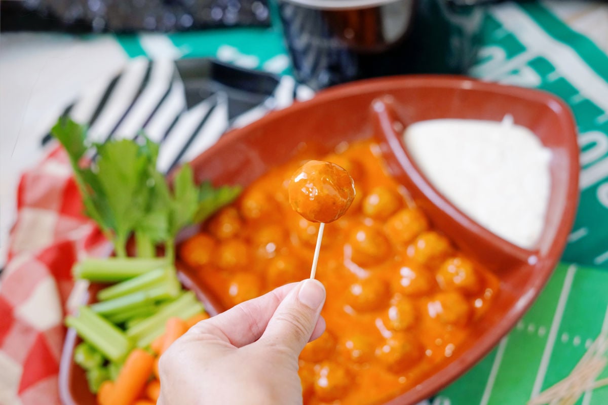 hand holding a buffalo meatball on a tooth pick