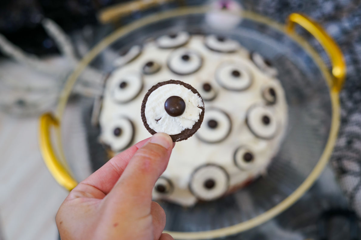 placing cookies and m&m's on Halloween cake