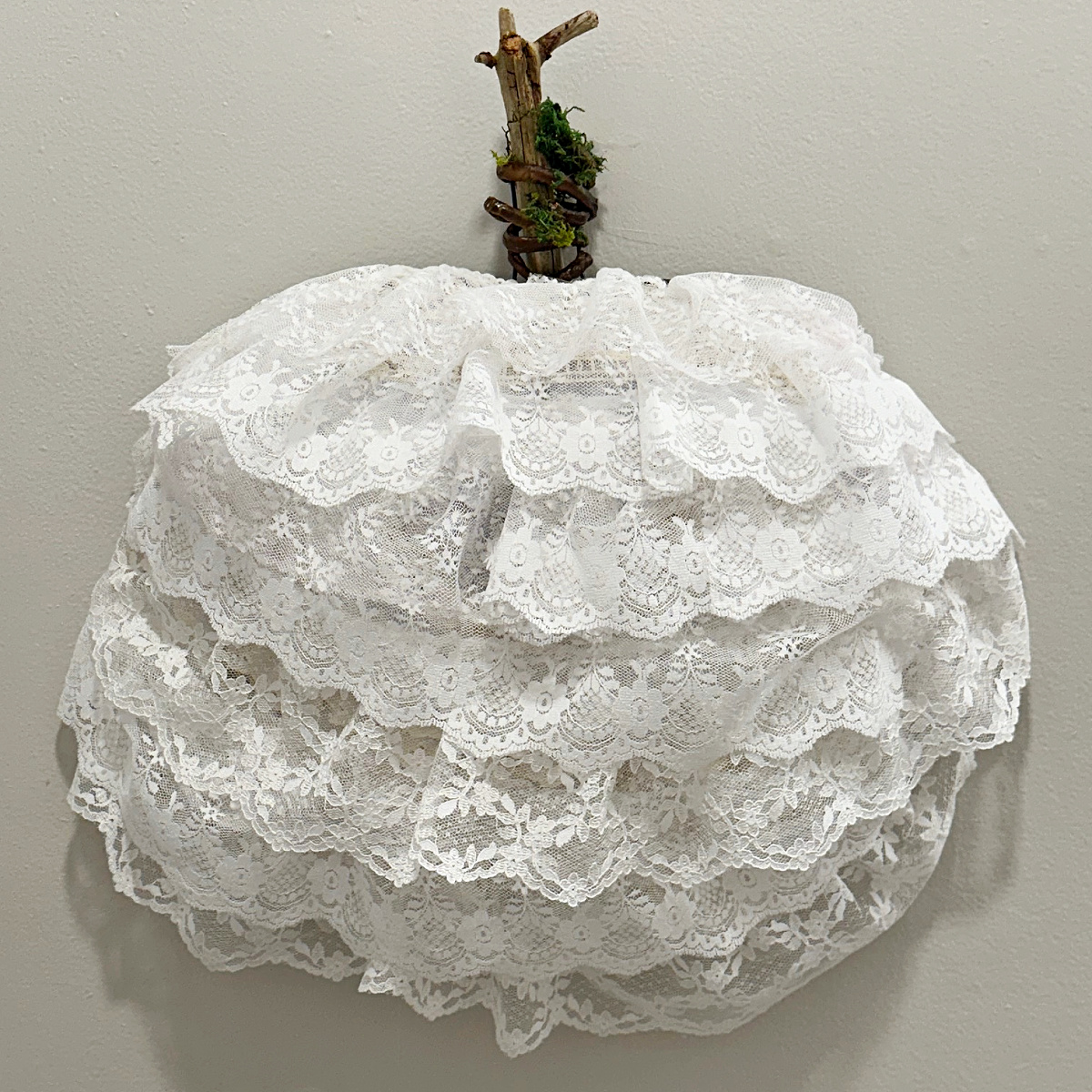 square image with close up of lace pumpkin wreath with wood stem